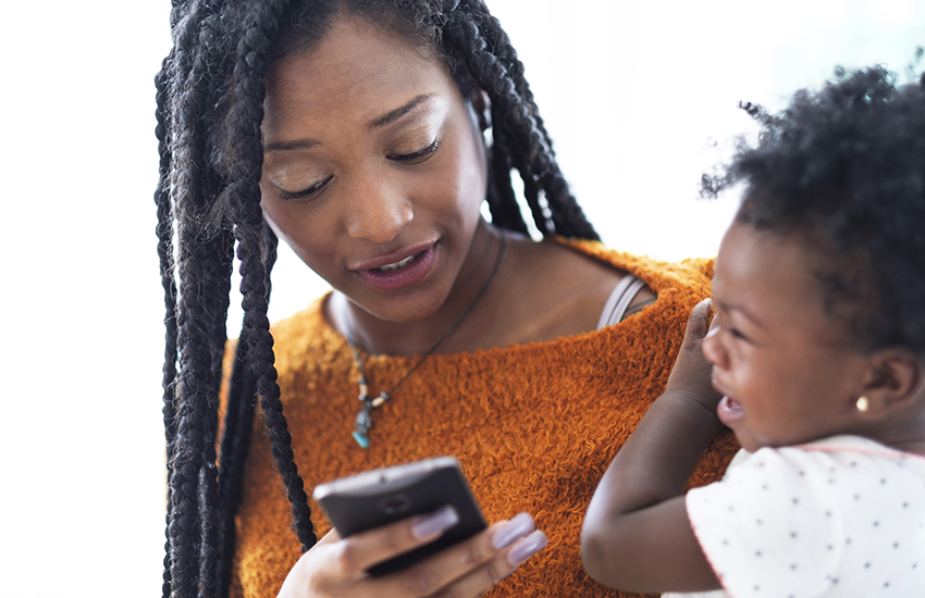 Une mère texte sur son cellulaire avec son enfant qui pleure