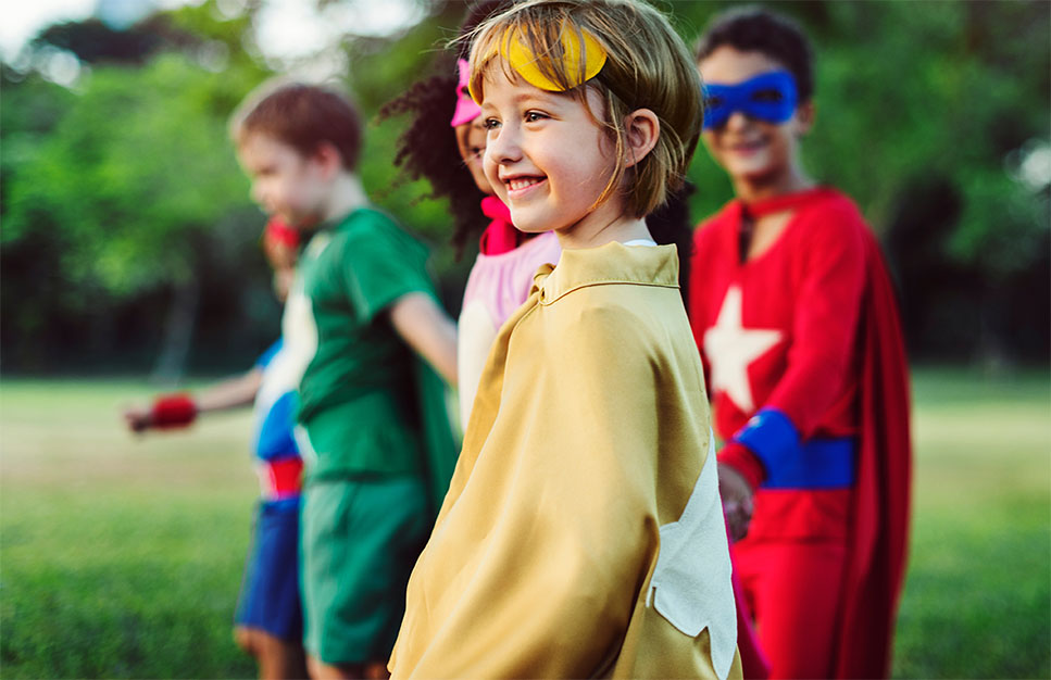 Enfants déguisés en superhéros participant à une activité communautaire en plein air. 