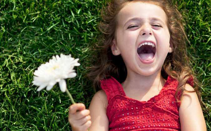 Une jeune fille rigole avec une fleur 