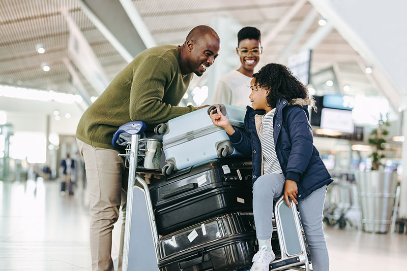 Famille de touristes avec un chariot à bagages à l'aéroport