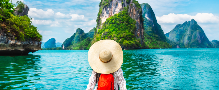 Femme avec chapeau de dos sur bord de l'eau en train d'admirer le paysage