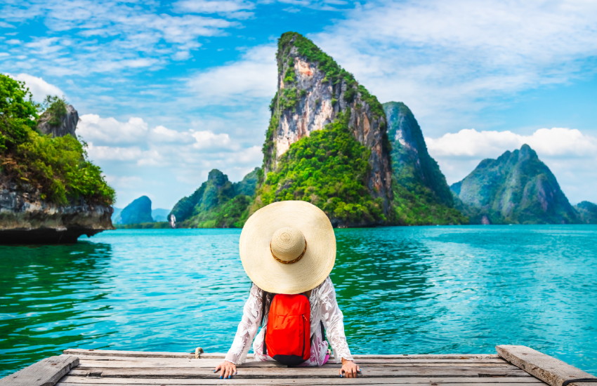 Femme avec chapeau de dos sur bord de l'eau en train d'admirer le paysage