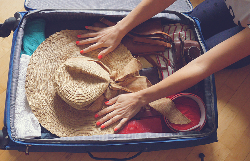Une valise remplie d'habits et et un chapeau