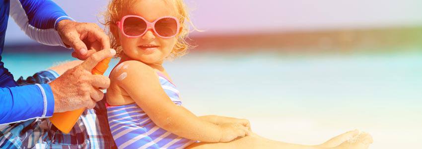 Une enfant met de la crème solaire à la plage