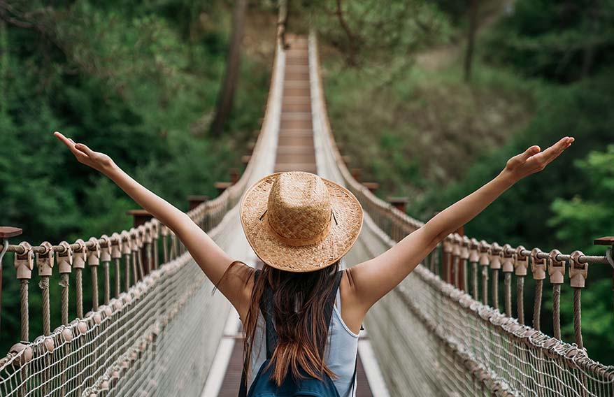 Femme heureuse en vacances, levant les bras dans les airs et profitant pleinement de son voyage. 