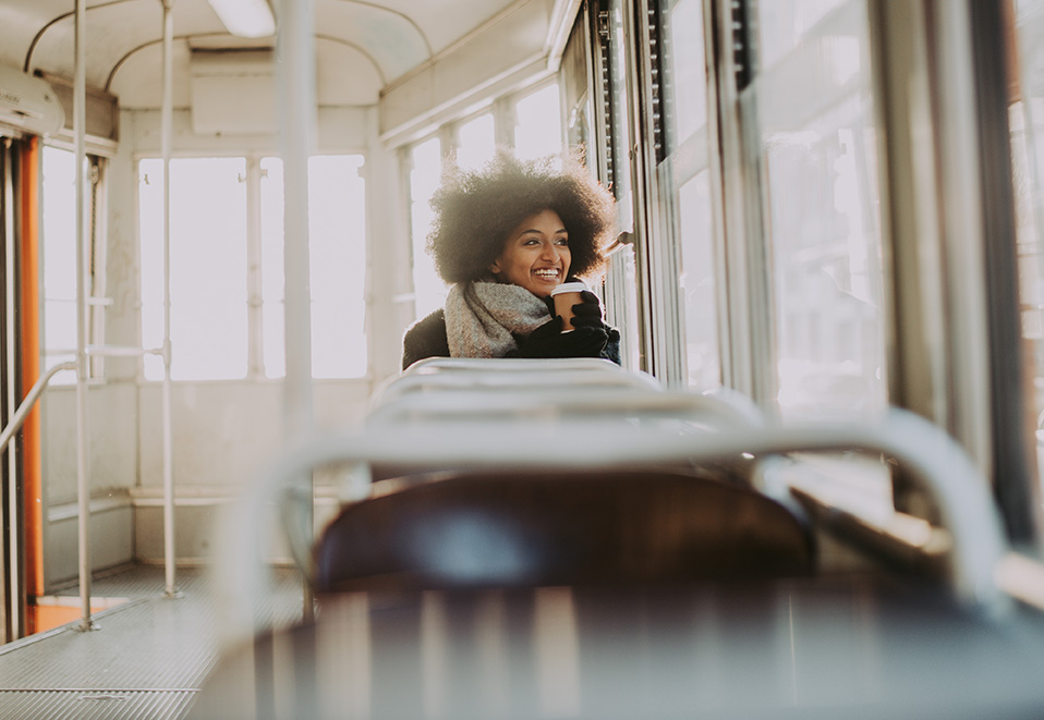 Personne assise dans un tramway baigné de lumière hivernale, profitant d’un moment calme en regardant dehors.