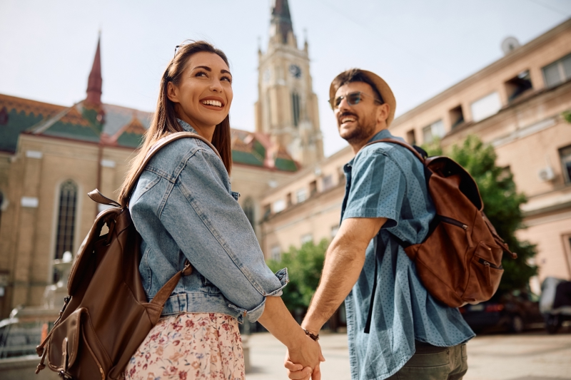 Jeune couple de voyageurs se tenant par la main lors d'une promenade dans une ville d'Europe.